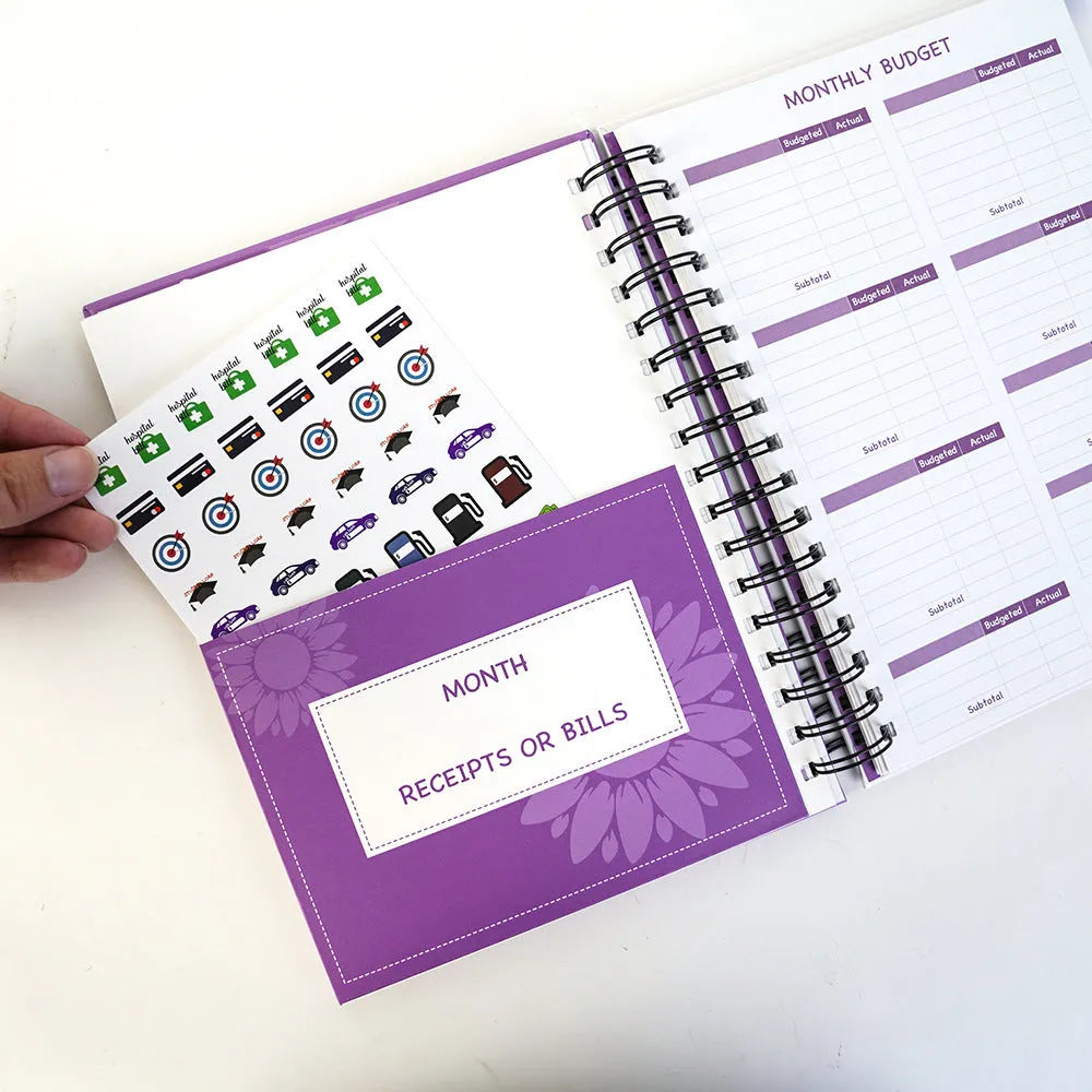 Purple A6 coil-bound budget notebook with pen and financial planning accessories