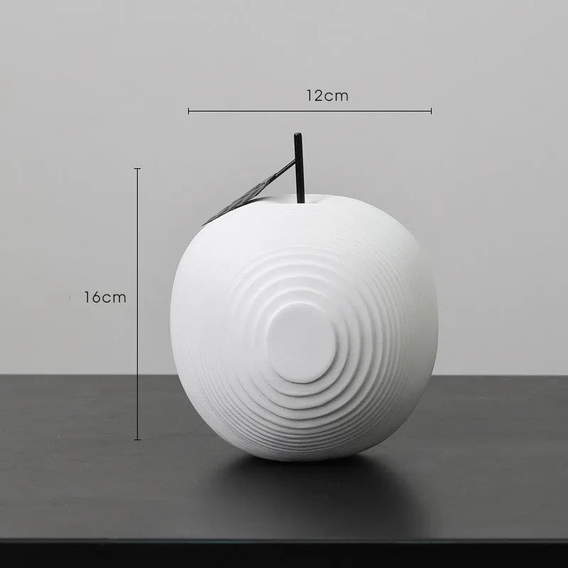 Resin decorative sculptures of apples and pears in black, white, orange and blue colours.