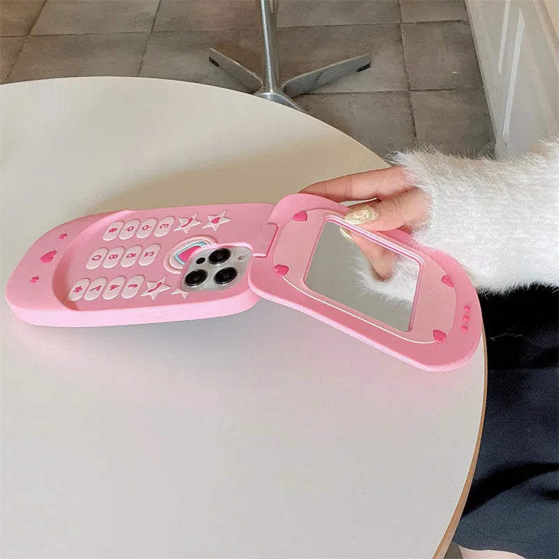 Pink silicone flip phone-shaped iPhone case with a built-in mirror and cute cartoon design.