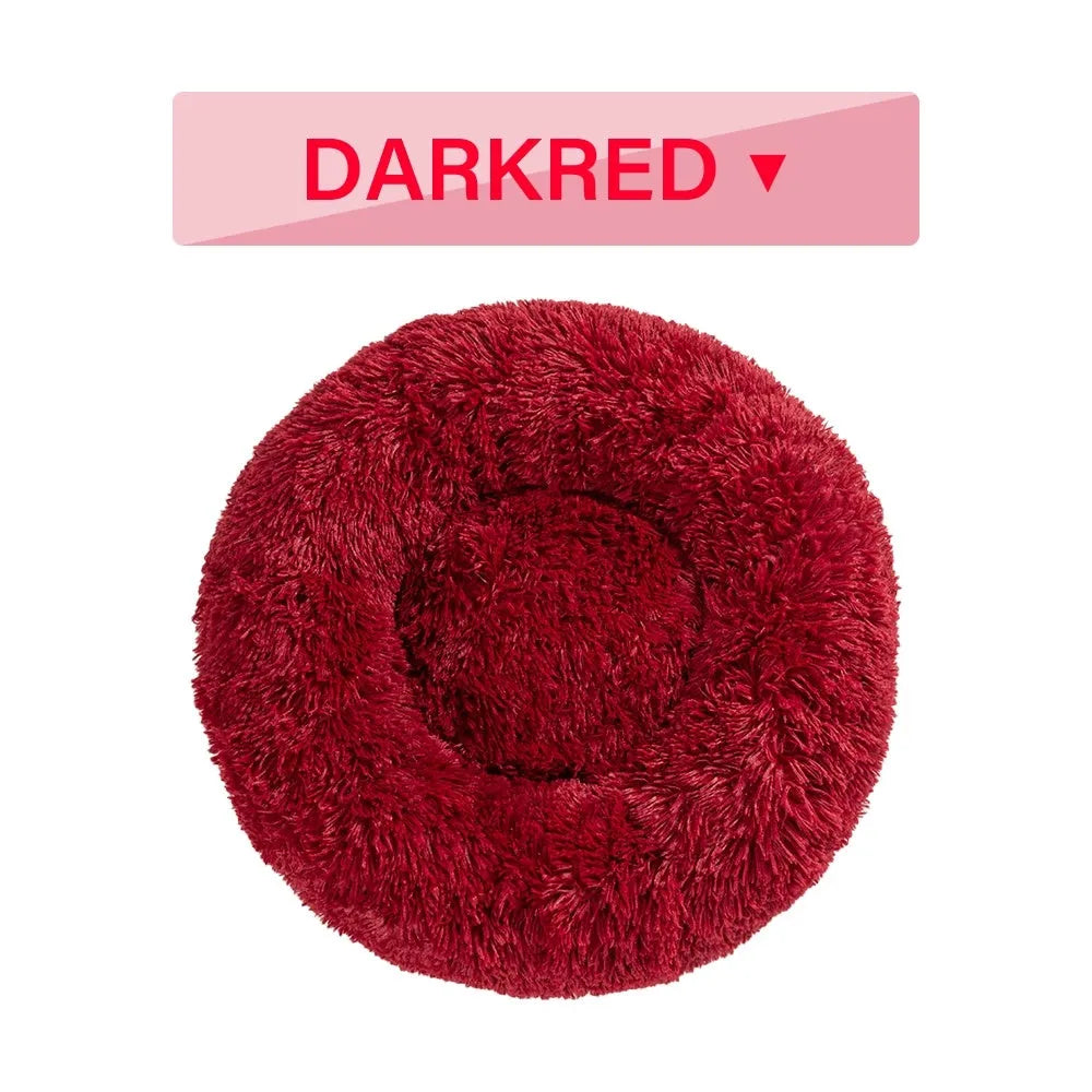 Fluffy donut-shaped dog bed in long plush material, shown in a light grey colour with a raised edge.