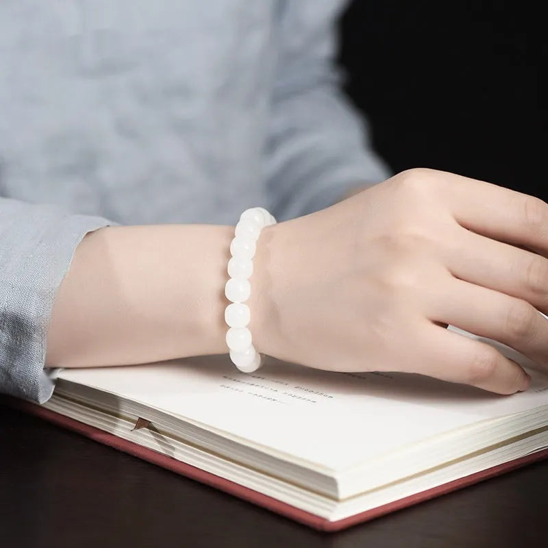 White Hetian jade barrel bead bracelet on a wrist, showing traditional unisex design.