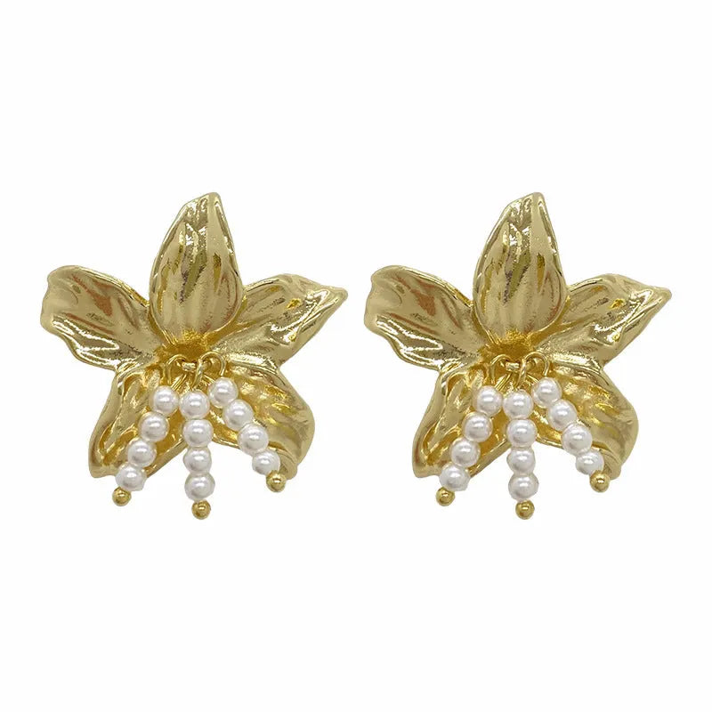 A pair of exaggerated gold metal flower earrings with pearls, showing niche style design.