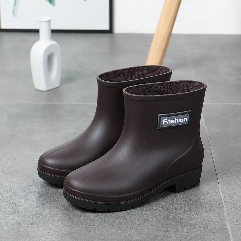 Women's mid-calf PVC rain boot in black on a wet surface.