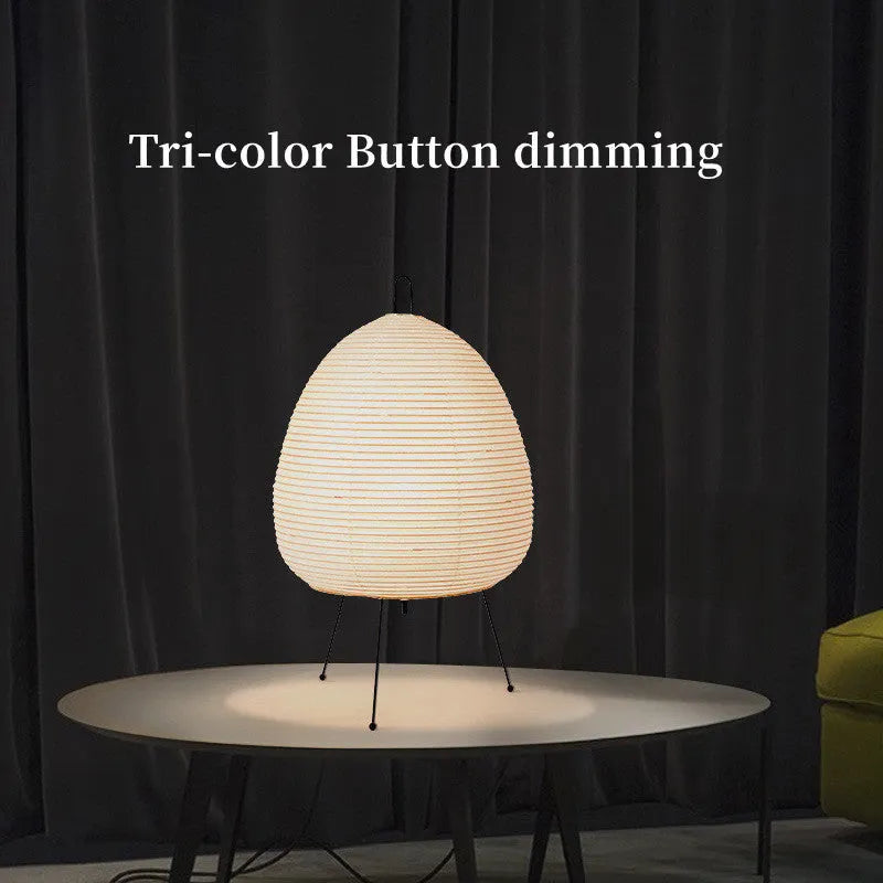 Japanese style handmade rice paper lantern table lamp with aluminium base on a wooden table.