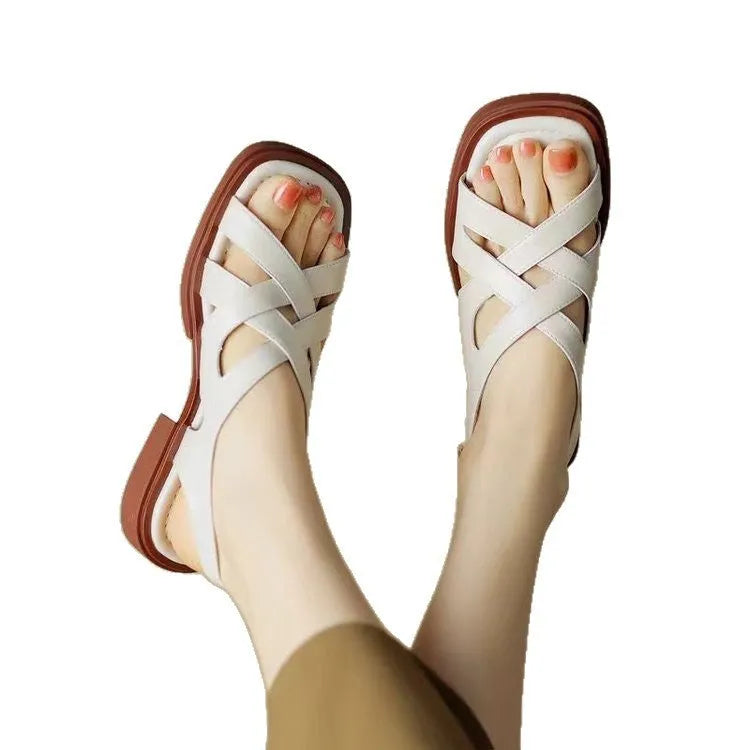 Women's black patent leather low heel sandals with square toe and cross ankle strap.