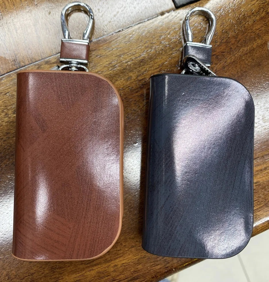 Black frosted leather car key case with zipper, next to a car key