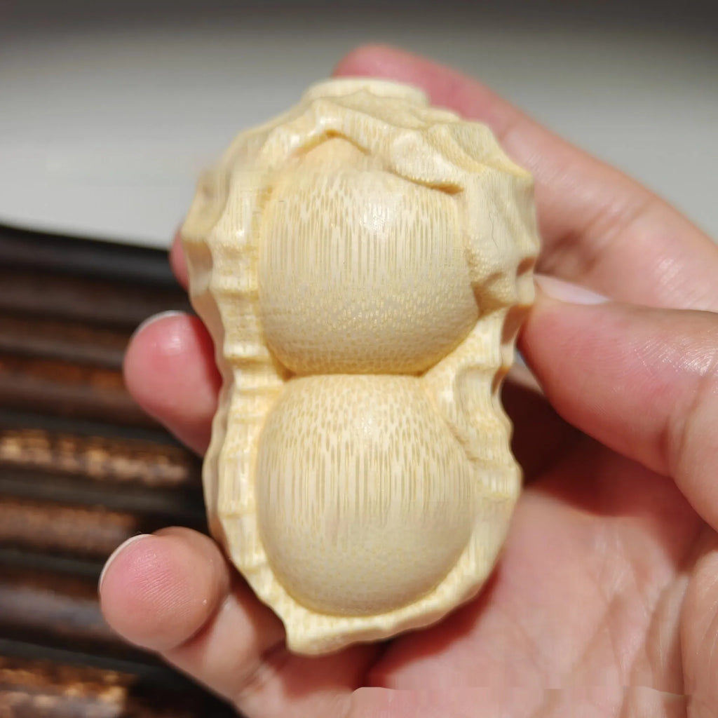 Solid natural bamboo hand-carved peanut ornament on a plain background.