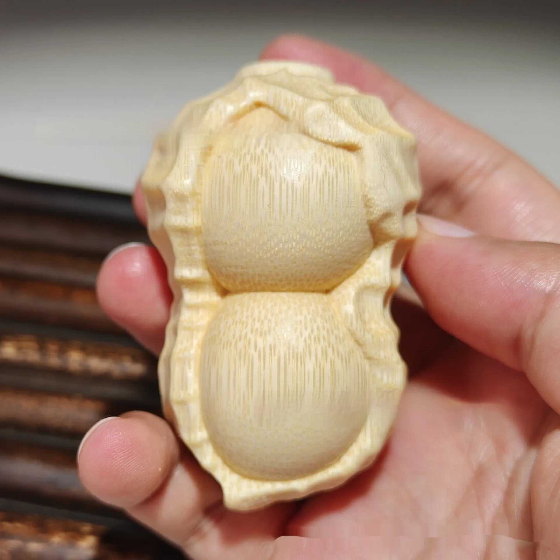 Solid natural bamboo hand-carved peanut ornament on a plain background.