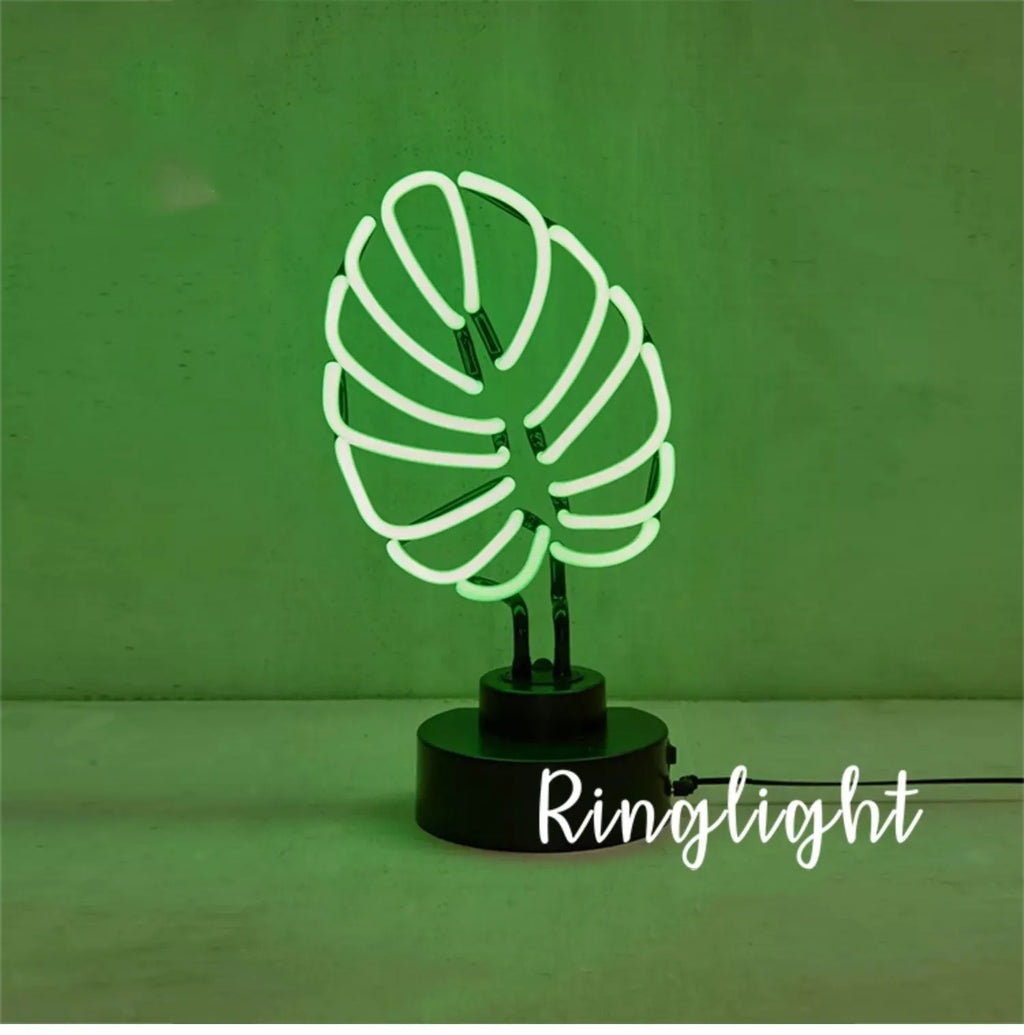 White bamboo-shaped desktop lamp with green light tube on a wooden desk.
