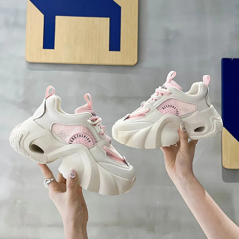 Women's beige sneakers with a cross shoulder strap and thick rubber sole on a white background.