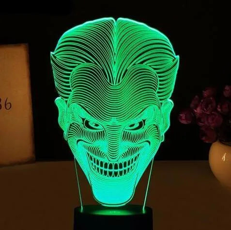 3D LED table lamp showing seven colour options with remote control and USB cable on wooden surface