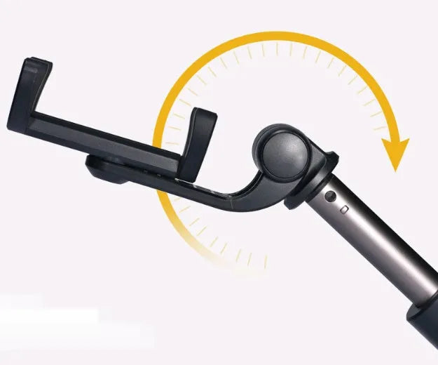 Black Bluetooth selfie stick with extended tripod legs and remote control next to a mobile phone.