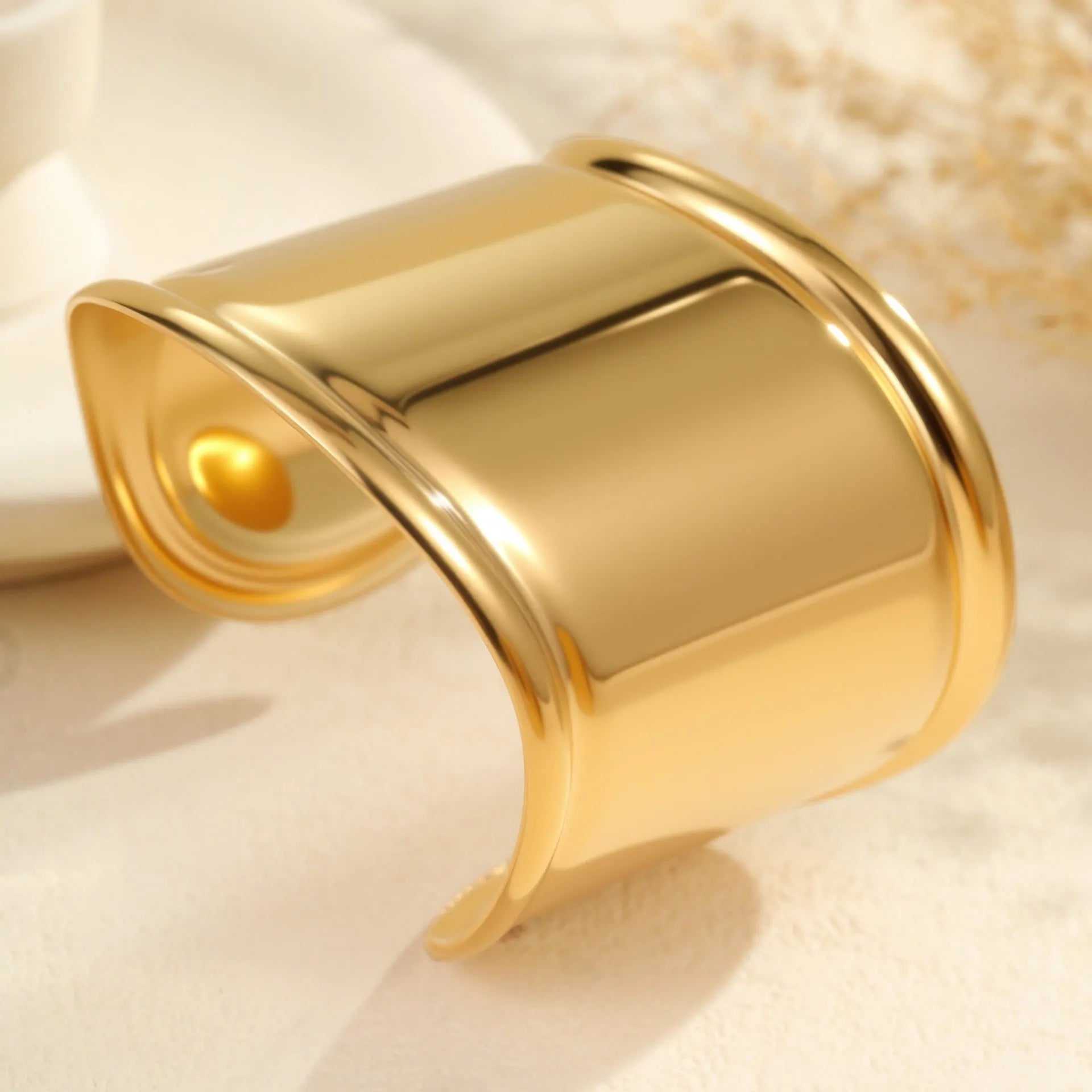 Women's wide stainless steel bracelet with 18K gold plating showing geometric wave patterns