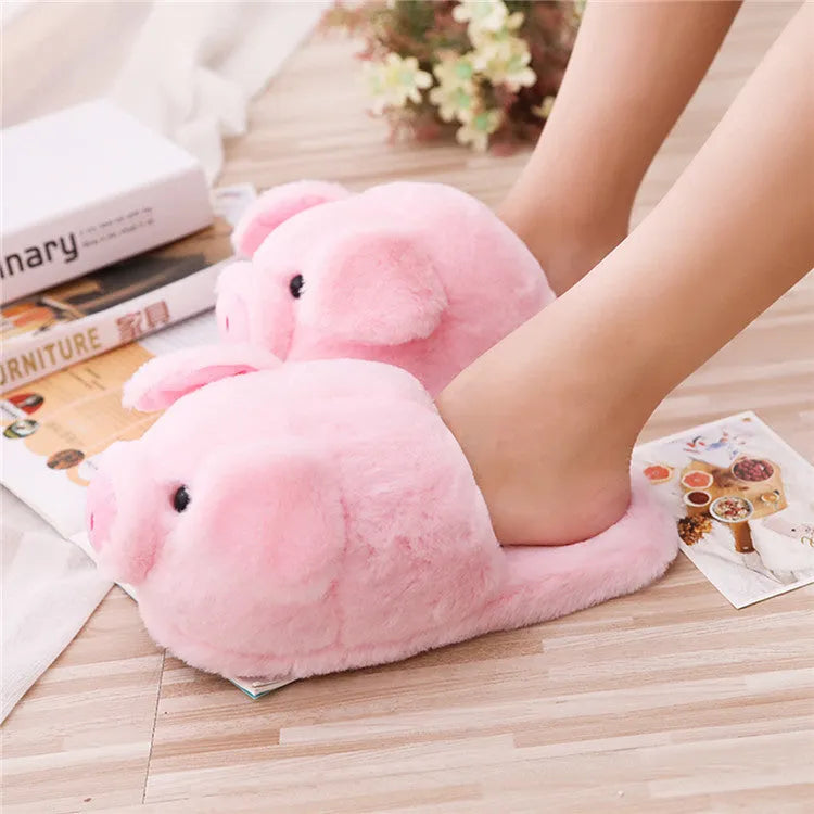 Pink pig-shaped plush slippers for adults on a white background.