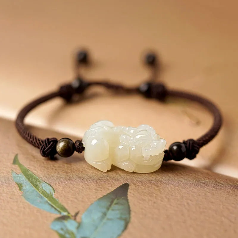 A Hetian jade bracelet with braided black and red rope in a Chinese style design.