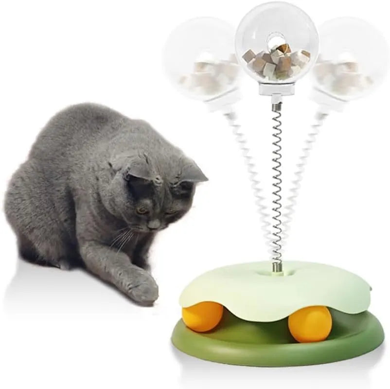 Blue and green cat treat dispenser toy with track ball on a wooden floor