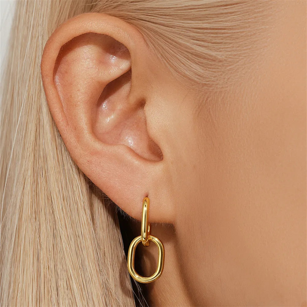 A pair of simple geometric brass earclip earrings with a round element and electroplated golden finish.