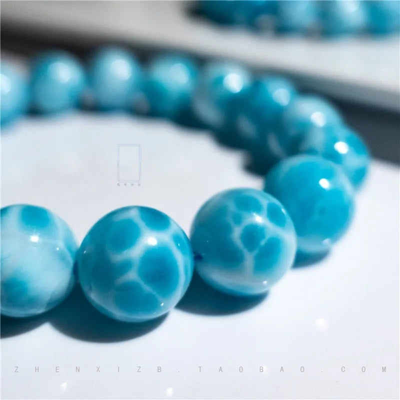 Blue natural Bodhi seed and crystal sea-pattern stone bracelet with a single pearl accent on a wrist.
