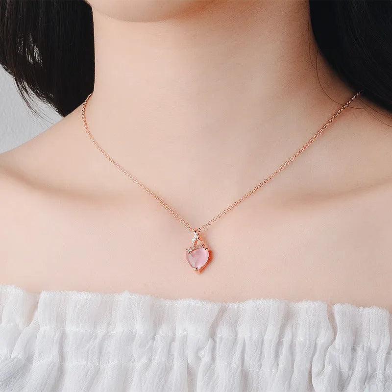 Rose gold cross chain necklace with a pink heart-shaped synthetic crystal pendant.