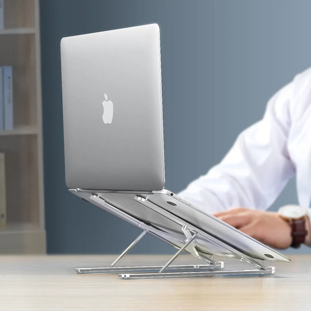 A folded aluminium laptop stand in silver next to an open laptop, demonstrating its compact size.