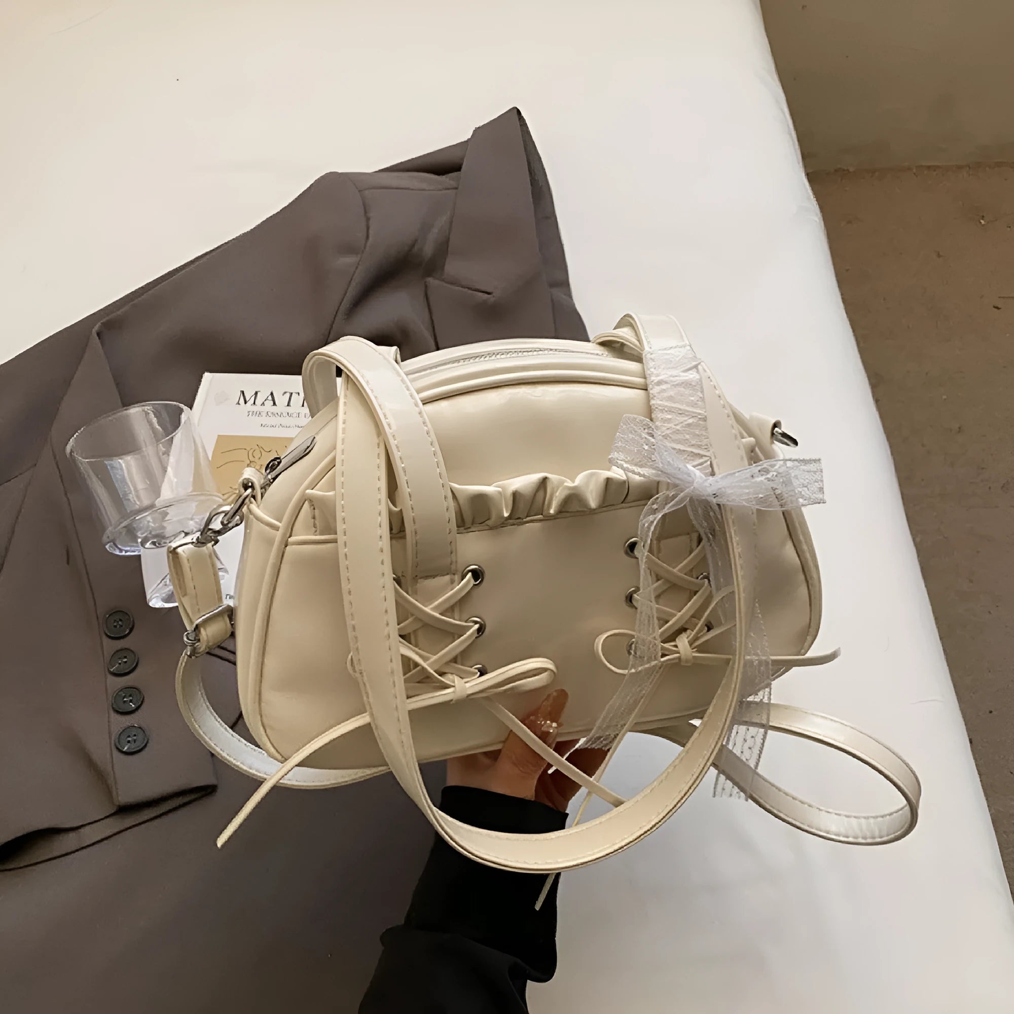 Milky white women's PU shoulder bag with a black bandage bow and sewing thread detail.