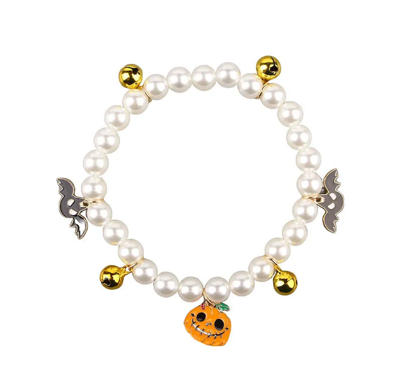 Adjustable simulated pearl necklace cat collar with a Halloween pumpkin charm in purple ghost, skull, or smile designs.