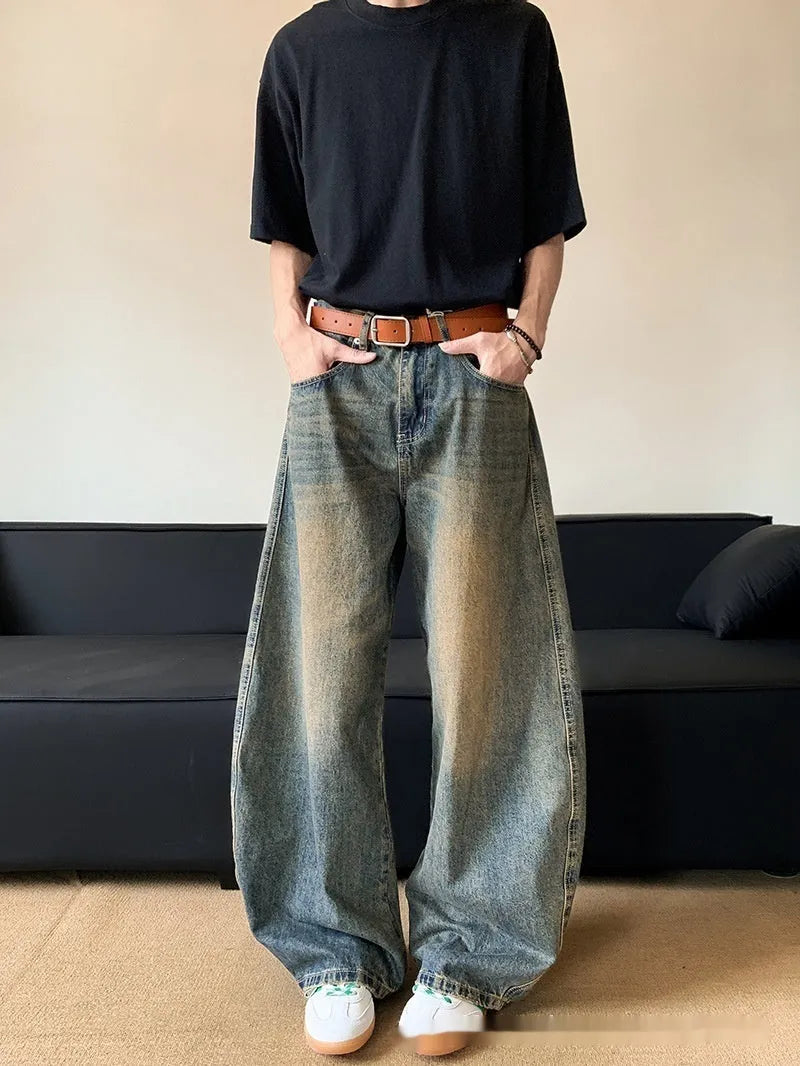 Man wearing retro blue distressed denim jeans with a slim-fit wide-leg cut.