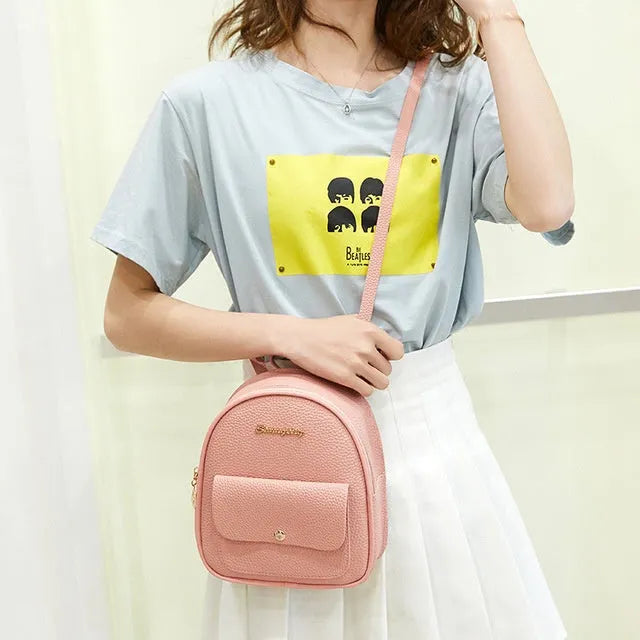 Small black PU shoulder backpack for women with zipper, shown next to a mobile phone for scale.