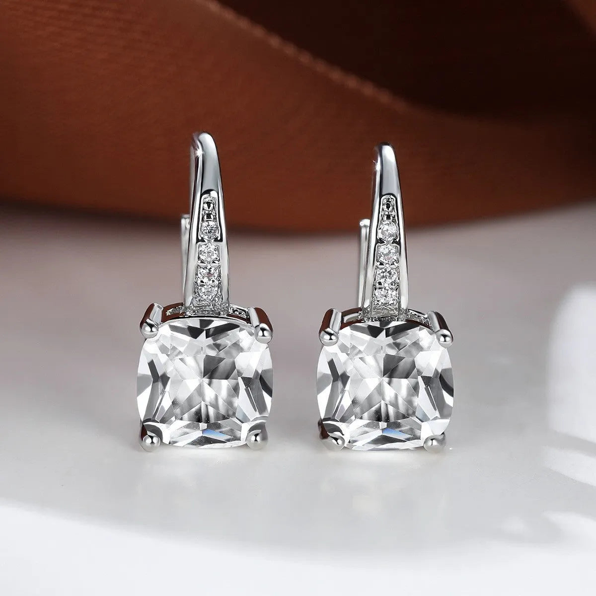 Square geometric ear hook earrings with zircon stones in an electroplated copper setting.