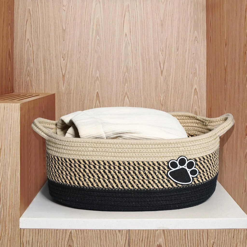 Small light beige handmade cotton rope storage basket with wooden handle on a table.