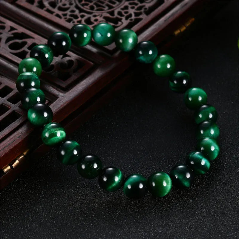 Polished green tiger eye stone bead bracelet with geometric beads on a wrist.