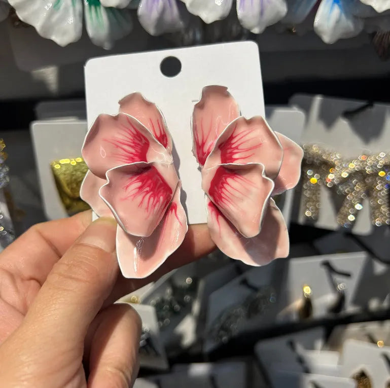 Close-up of alloy floral stud earrings with oil-spot glaze in blue, green, purple, and rose colour options.