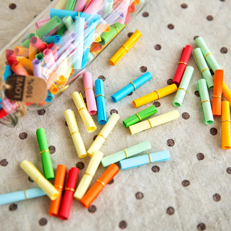 Colourful assortment of small paper scrolls with metal eyelets for drift bottle messages.