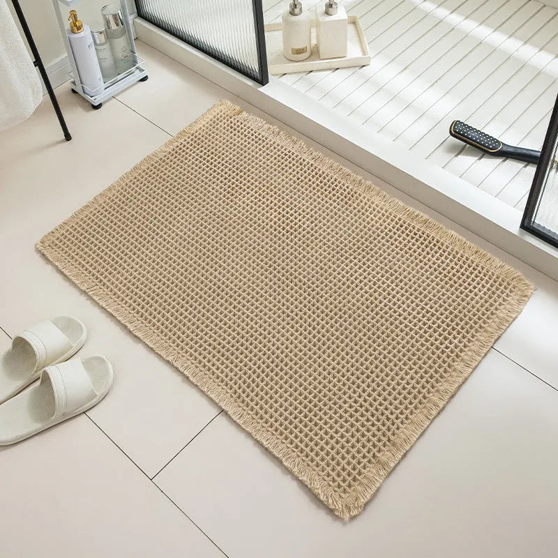 Square checkered-pattern non-slip bathroom carpet in a neutral colour on tiled floor.