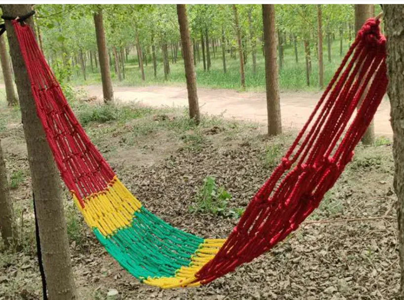 Nylon rope mesh hammock hung between two trees with tying rope visible