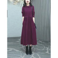 Purplish red plus size women's dress with long skirt and extra-long sleeves on a model.