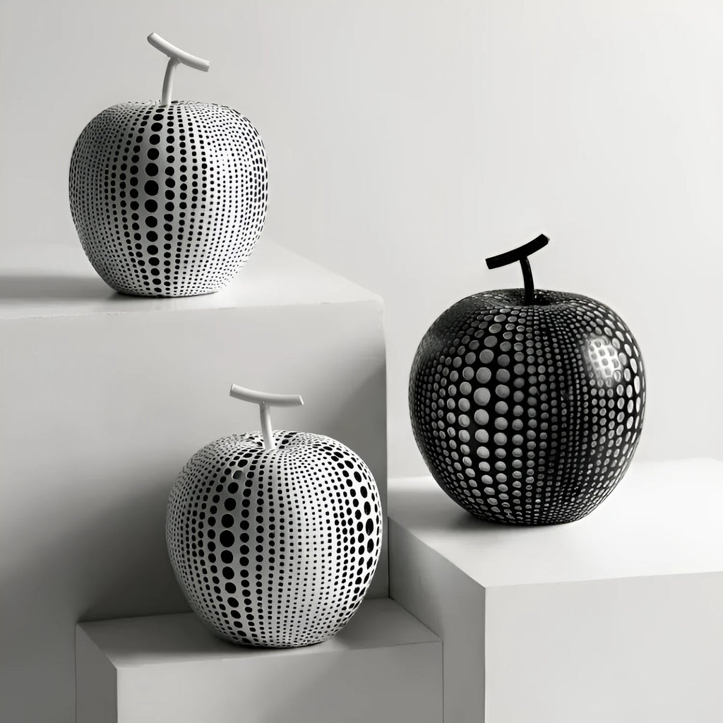 Resin decorative sculptures of apples and pears in black, white, orange and blue colours.
