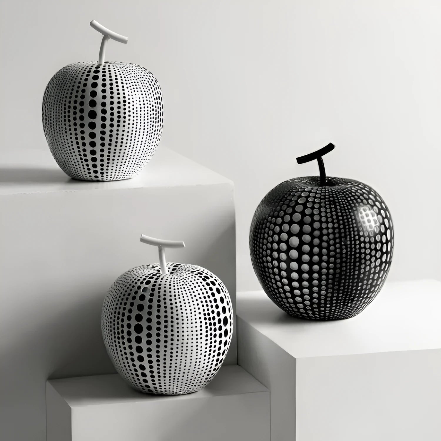 Resin decorative sculptures of apples and pears in black, white, orange and blue colours.