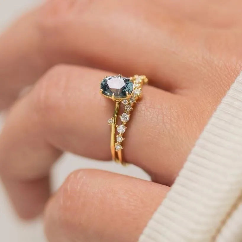 Gold electroplated floral-shaped alloy ring with a green zircon inlay on a white background.