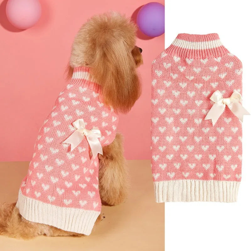 Dog wearing acrylic jumper with love heart and bow designs in red and pink colour patterns