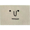Square PVC floor mat with a large cartoon face and geometric pattern in Mr. Big Nose colours on a home floor.