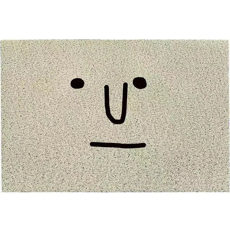 Square PVC floor mat with a large cartoon face and geometric pattern in Mr. Big Nose colours on a home floor.