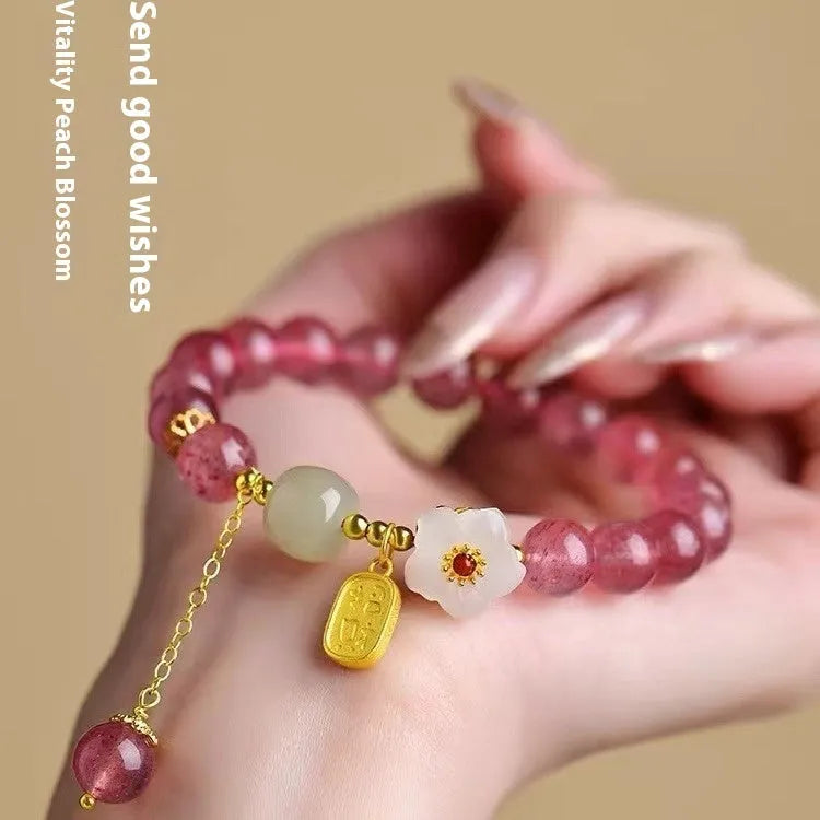 Handcrafted strawberry quartz crystal bracelet with peach blossom design on wrist
