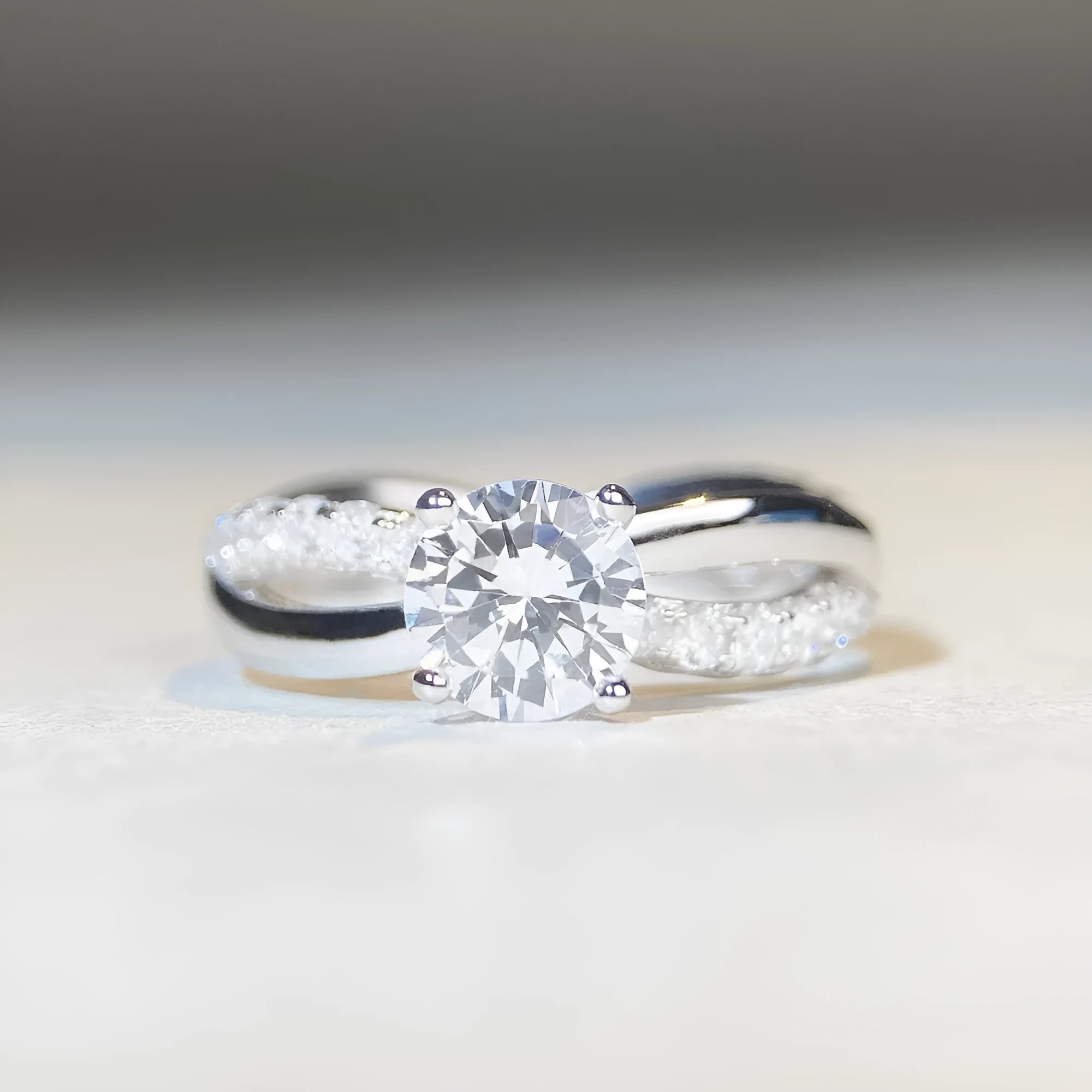 Silver geometric cross ring with a 1 karat moissanite stone in a four-claw setting on a twisted band.