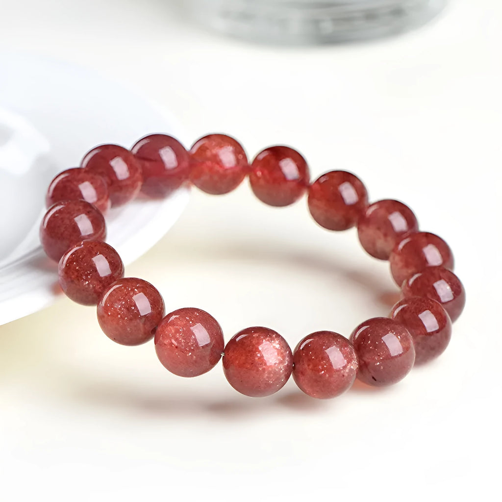 Natural cherry red strawberry quartz bracelet with geometry-shaped beads on a white background.