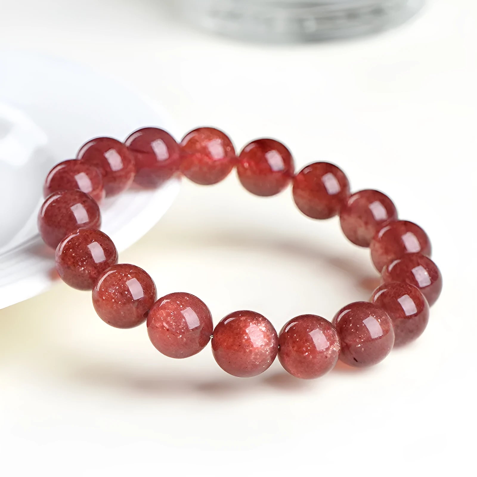 Natural cherry red strawberry quartz bracelet with geometry-shaped beads on a white background.