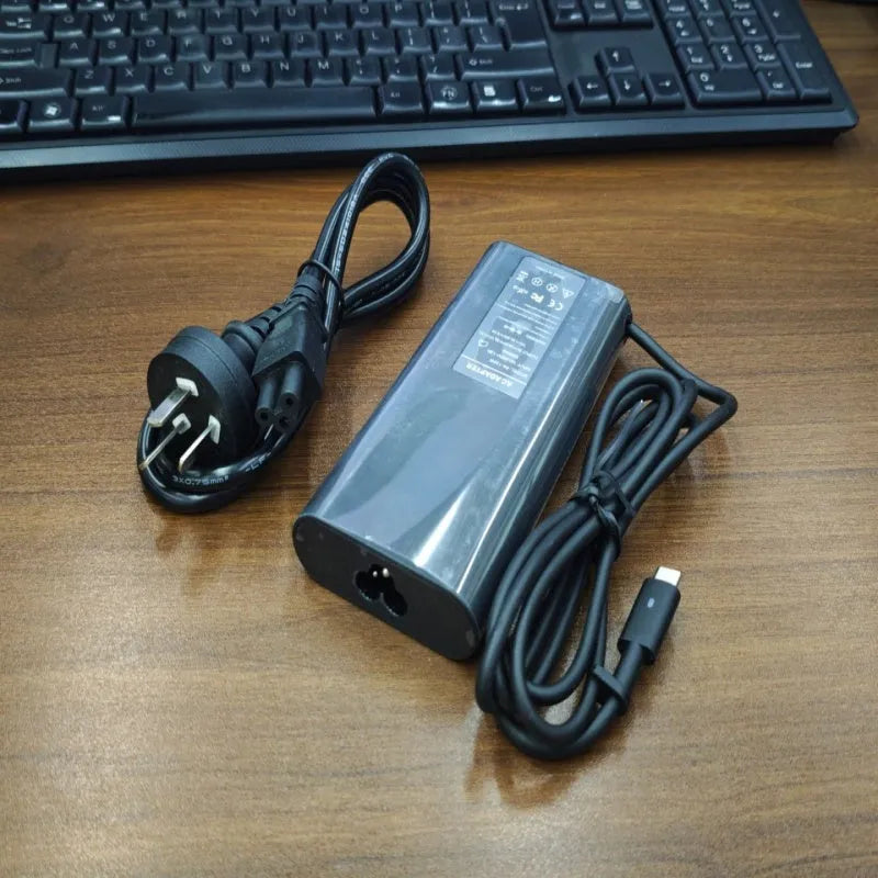 Black 65W Type-C laptop power adapter with multiple international power cords for UK US EU AU and ZA plugs.