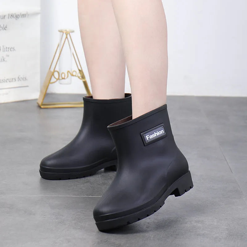 Women's mid-calf PVC rain boot in black on a wet surface.