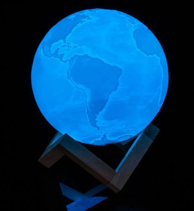 3D printed moon lamp glowing on a wood stand, showing detailed crater texture.