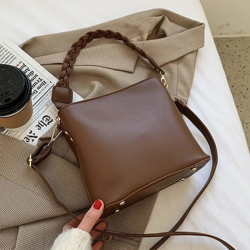 Khaki PU leather crossbody bucket bag with weaving texture and single shoulder strap.